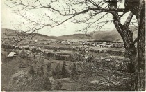 1909
Parna žaga Gaj (velika bela streha levo in pod farno cerkvijo) – pogled od Pušnika title=