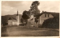 Cerkev sv. Lovrenca, v kateri je bila krščena Tončka;
spredaj sprva Društvéni, po vojni  Zadružni, zdaj Kulturni dom title=